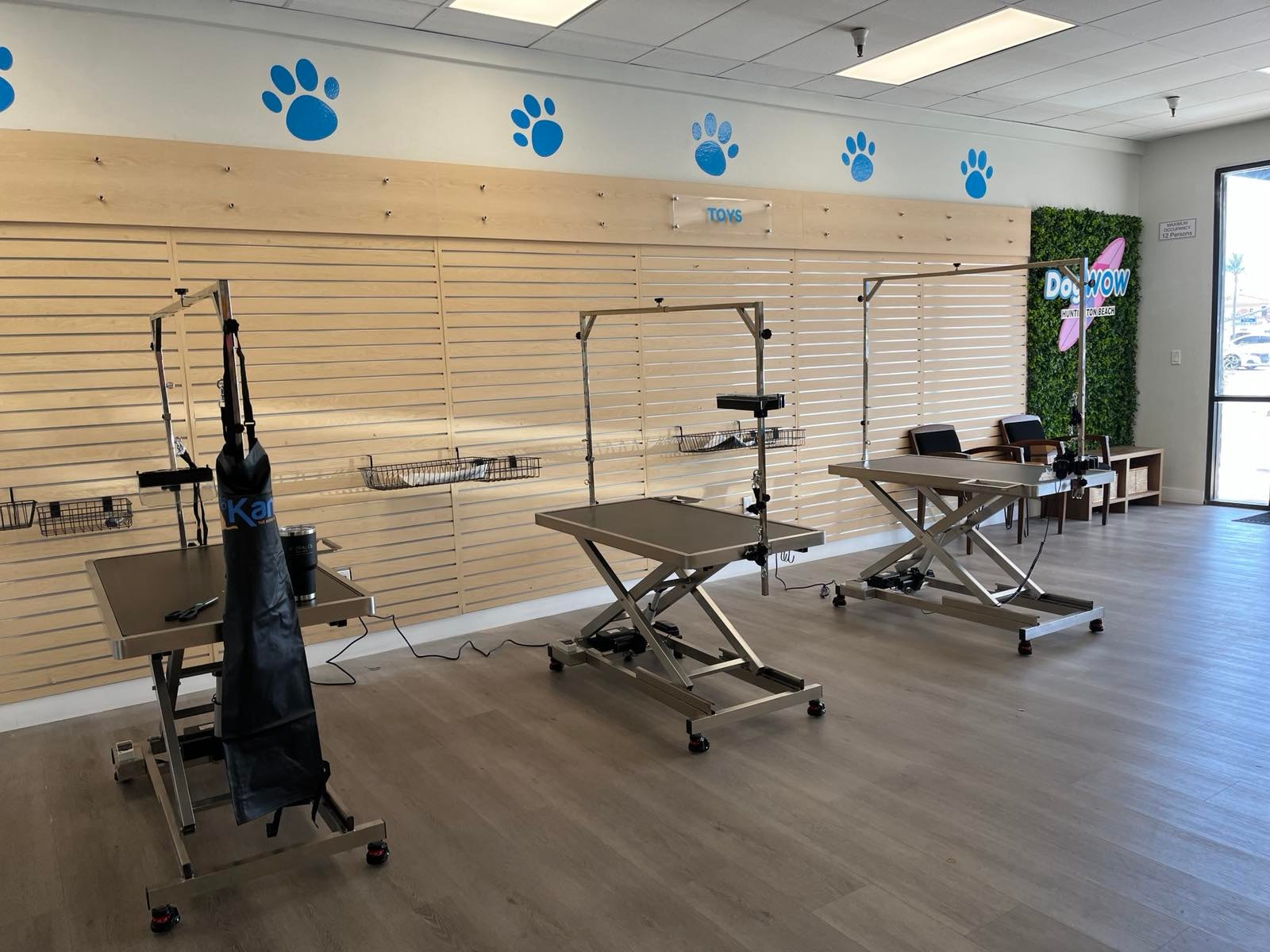 DOGWOW Huntington Beach professional grooming area with hydraulic grooming tables and wooden slatwall display
